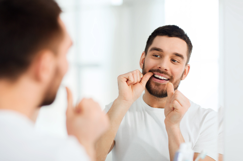 Prophylaxe – Mann mit Zahnseide
